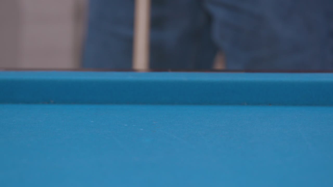 hombre golpeando la pelota en la mesa de billar azul