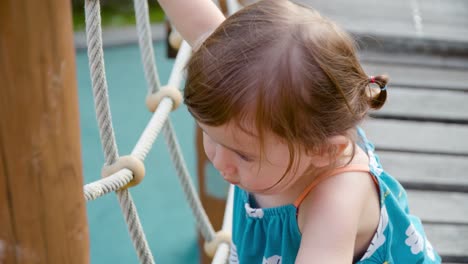 child moving through an outdoor obstacle course walking and balancing on the rope suspension bridge - slow motion close-up