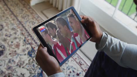 Compuesto-De-Hombre-Sentado-En-Casa-Viendo-Un-Evento-Deportivo-En-Una-Tableta