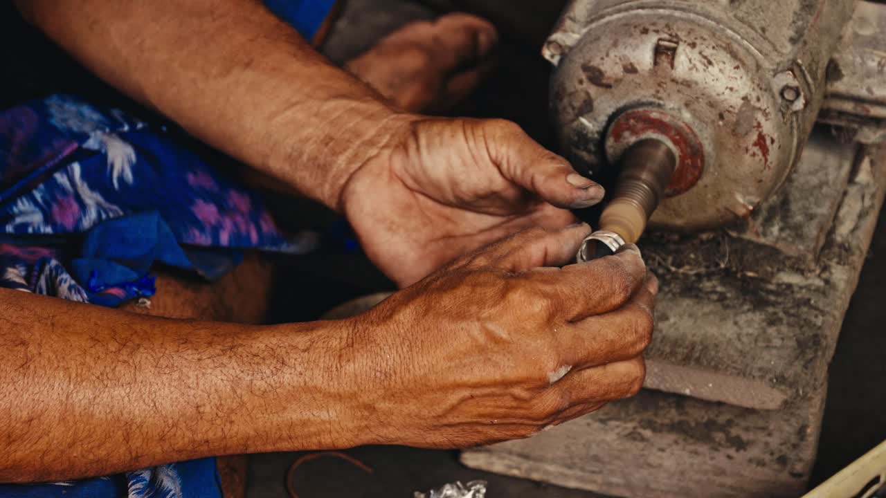 primer plano de un hombre pulindo un anillo de plata en un taller de fábrica en la zona rural de bali, indonesia