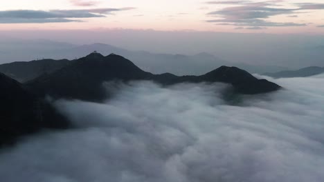 중국 홍콩 구룡봉의 푸른 시간에 산꼭대기를 덮고 있는 빽빽한 구름층 위로 날아가는 공중 인형