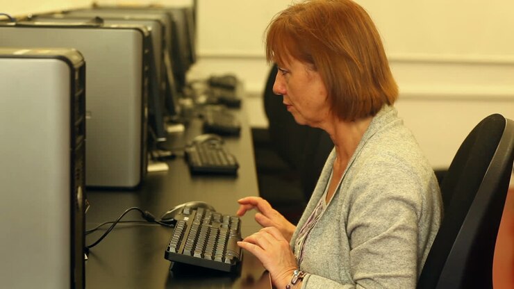 Mature student working with a computer sitting in computer room