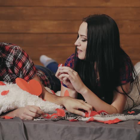 enamored man and woman are throwing into each other hearts by handmade on the bed on valentine's day
