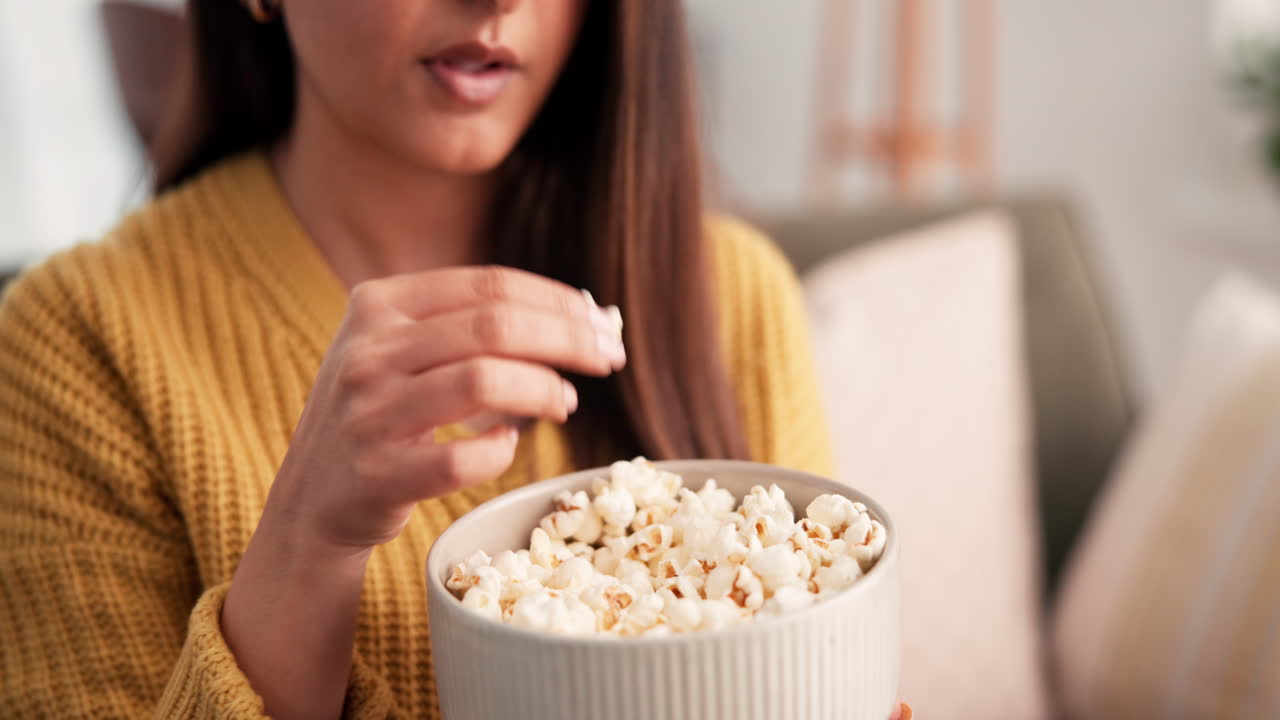 Donna che mangia popcorn sul divano