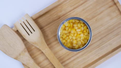 canned corn on wooden tray with utensils