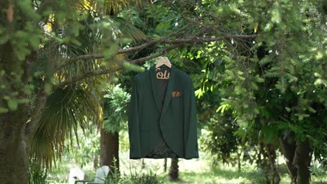 green groom's wedding suit on a hanger, suspended from a tree in an outdoor setting