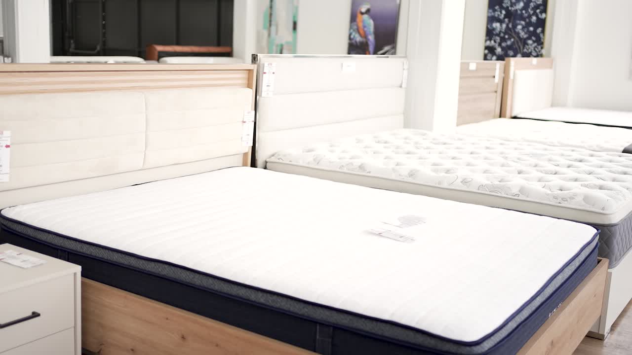 Customers browse a collection of mattresses in a sleep store, comparing styles and features. Many options are available for those seeking better sleep quality