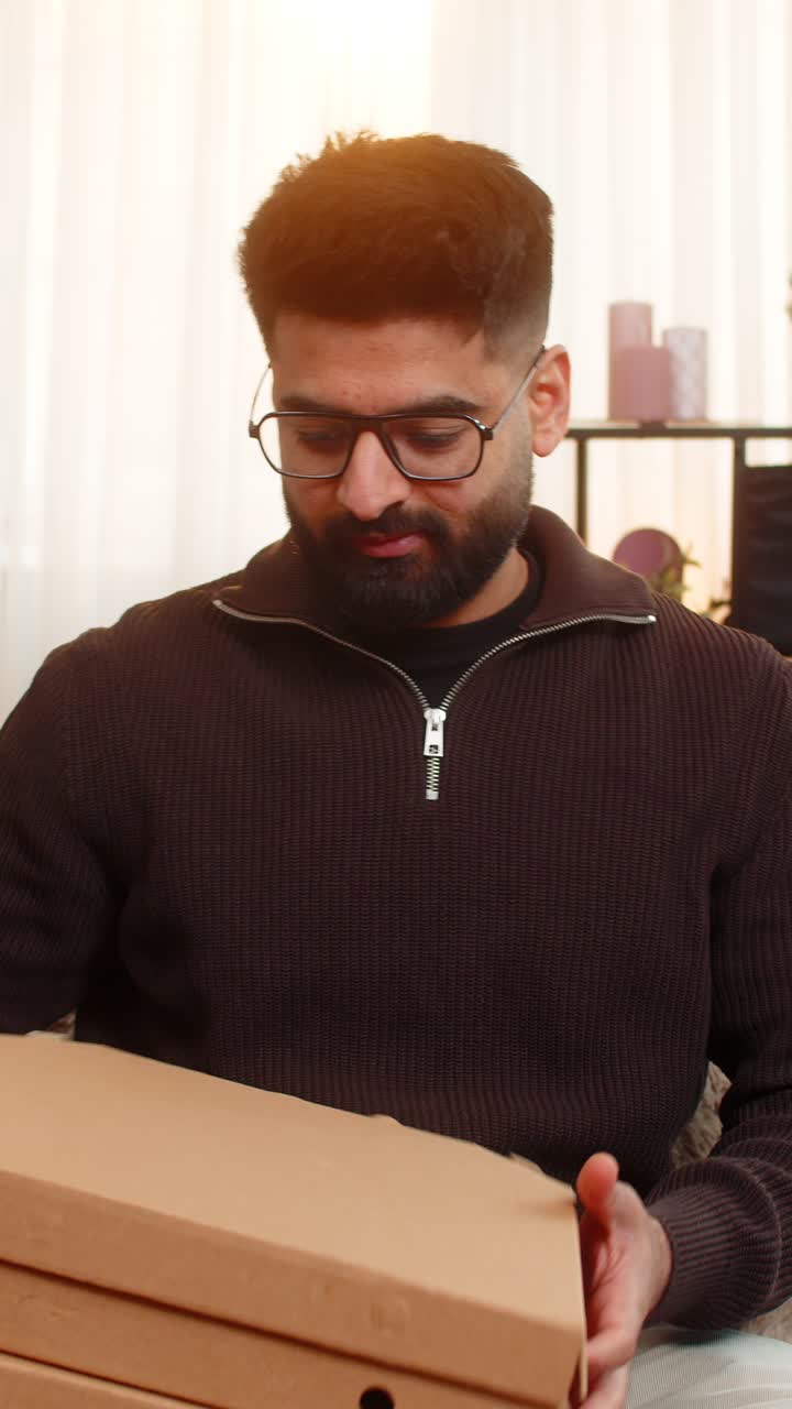 Indian man happily shops online using credit card and smartphone excited about new food delivery