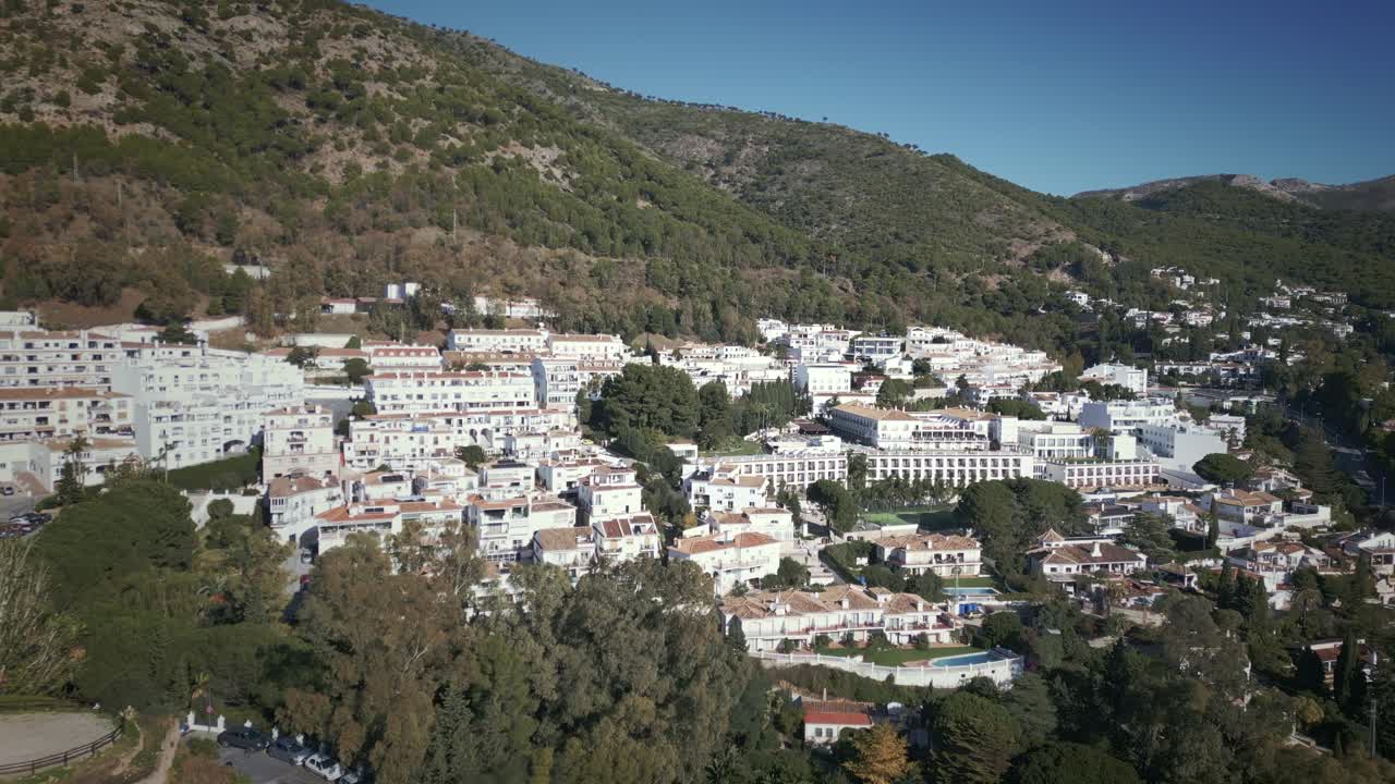 Vista aérea de Mijas Pueblo, Málaga, Espanha, com casas nas encostas e arquitetura tradicional caiada de branco cercada por vegetação exuberante