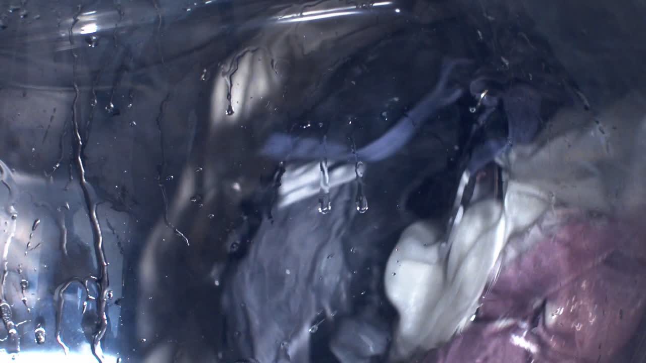 primer plano de la vista a través de la ventana de una lavadora durante un ciclo de lavado