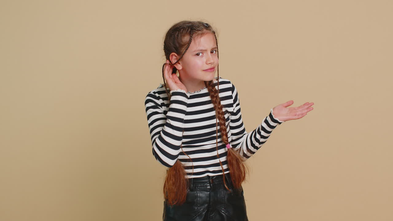 """아이, 소녀, 소년, 당신을 들으려고 애쓰고, 혼란스러워 보이고, 눈살을 푸리며, 더 큰 목소리를 내기 위해 귀에 팔을 고 있습니다."""