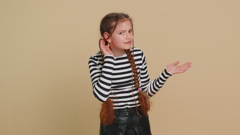 child girl kid trying hear you looking confused and frowning keeping arm near ear for louder voice