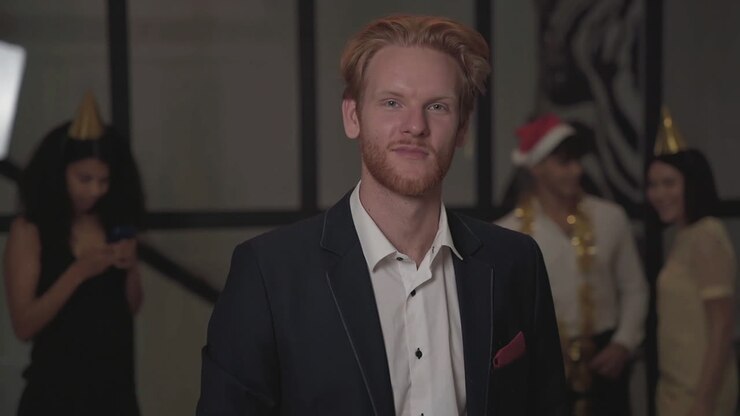 Jonge blije man kijkt in de camera en proost op een oudejaarsavondfeest.