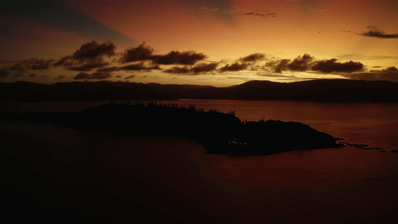 Daydream Island in the Australia at sunset with a bright orange sky and clouds