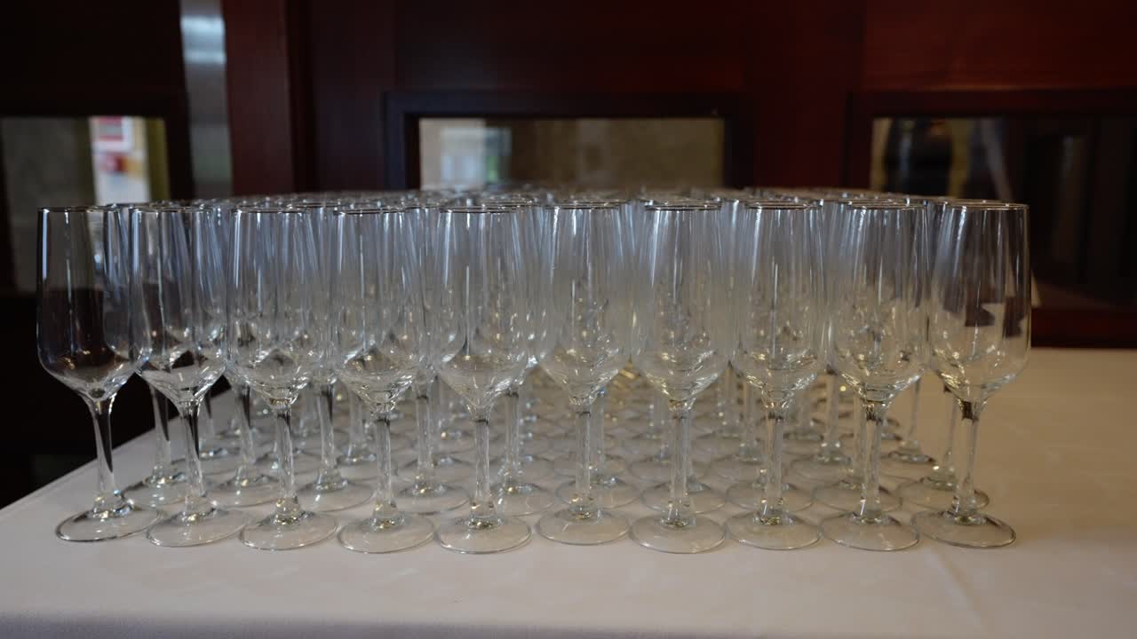 Flûte di champagne allineate su un tavolo da banchetto in una sala da ballo di un hotel, pronte per il brindisi e i festeggiamenti degli ospiti durante il ricevimento nuziale