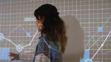 Female-Teacher-Giving-Maths-Or-Science-Lesson-In-College-Or-University-Standing-At-The-Front-Of-Class-With-Projection-Of-Graph-8