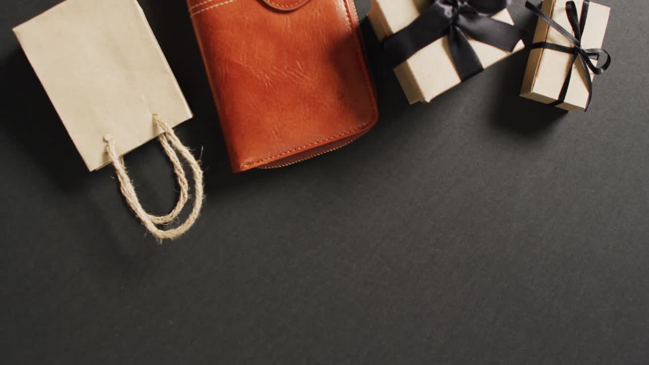 bolso de cuero, bolsa de regalos y cajas de regalos con cintas negras sobre fondo negro con espacio para copiar