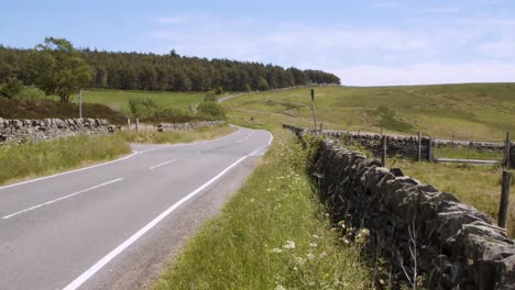 vehicles driving past on a small highway running through the moorlands of derbyshire, england