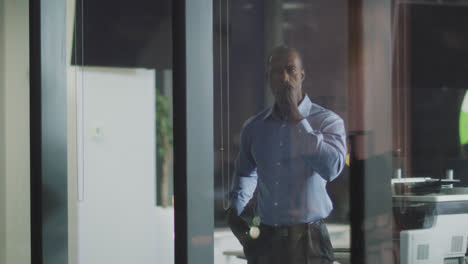 Thoughtful-professional-businessman-looking-through-a-window-while-his-hand-on-his-chin-in-slow-moti