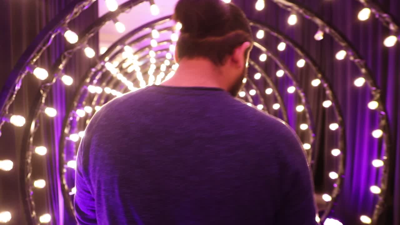 보라색 색상의 전구로 장식된 터널을 걷는 청년, 미래 지향적인 분위기
