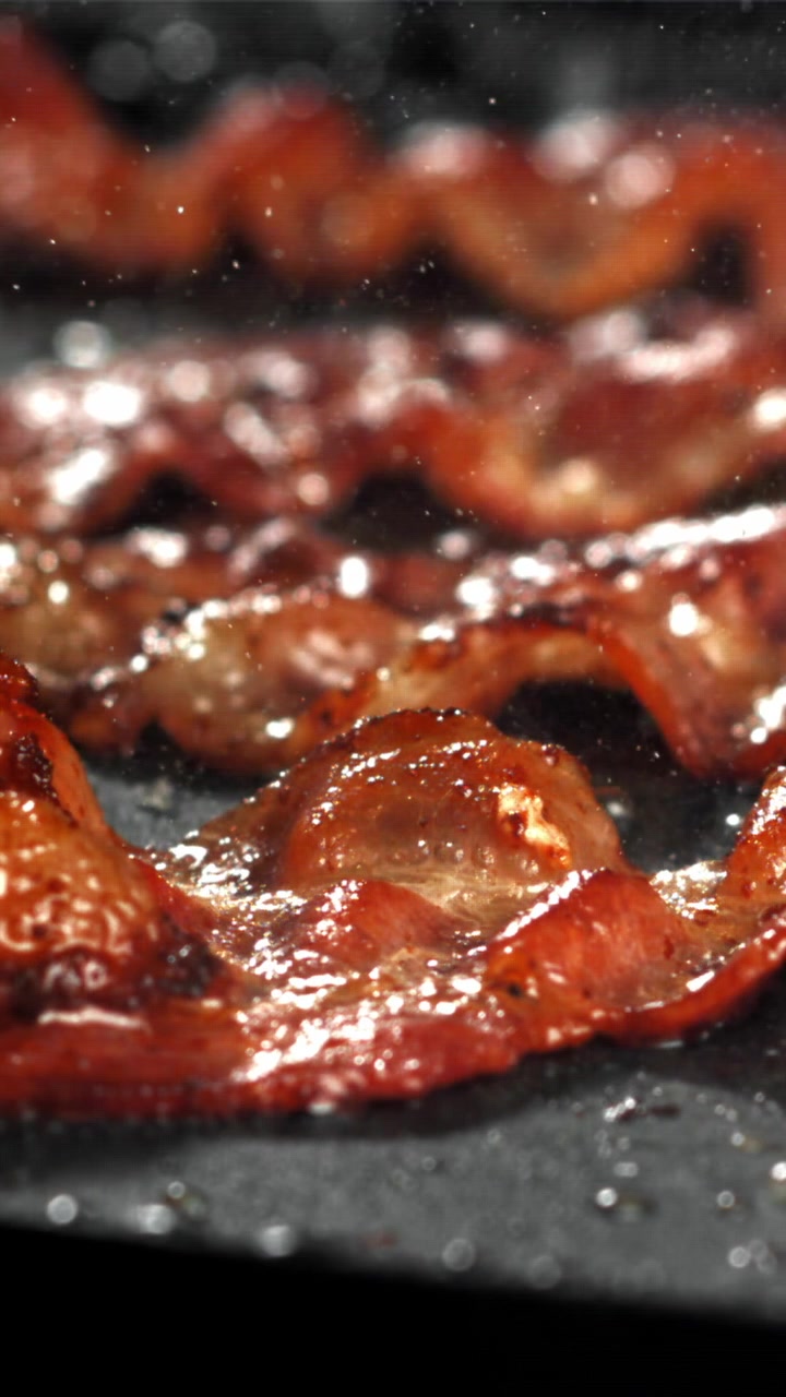 Bacon croccante che sfrigola in una padella calda