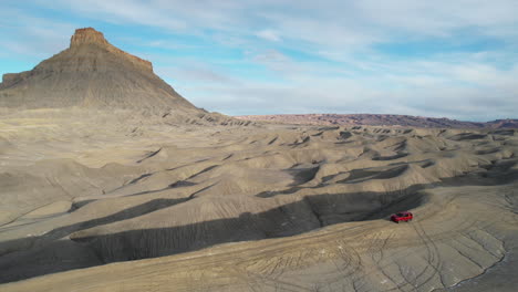 drone shot red off road vehicle moving on hill in desert landscape of utah usa