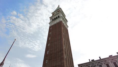 st mark's campanile on bright sky with white clouds in venice, italy