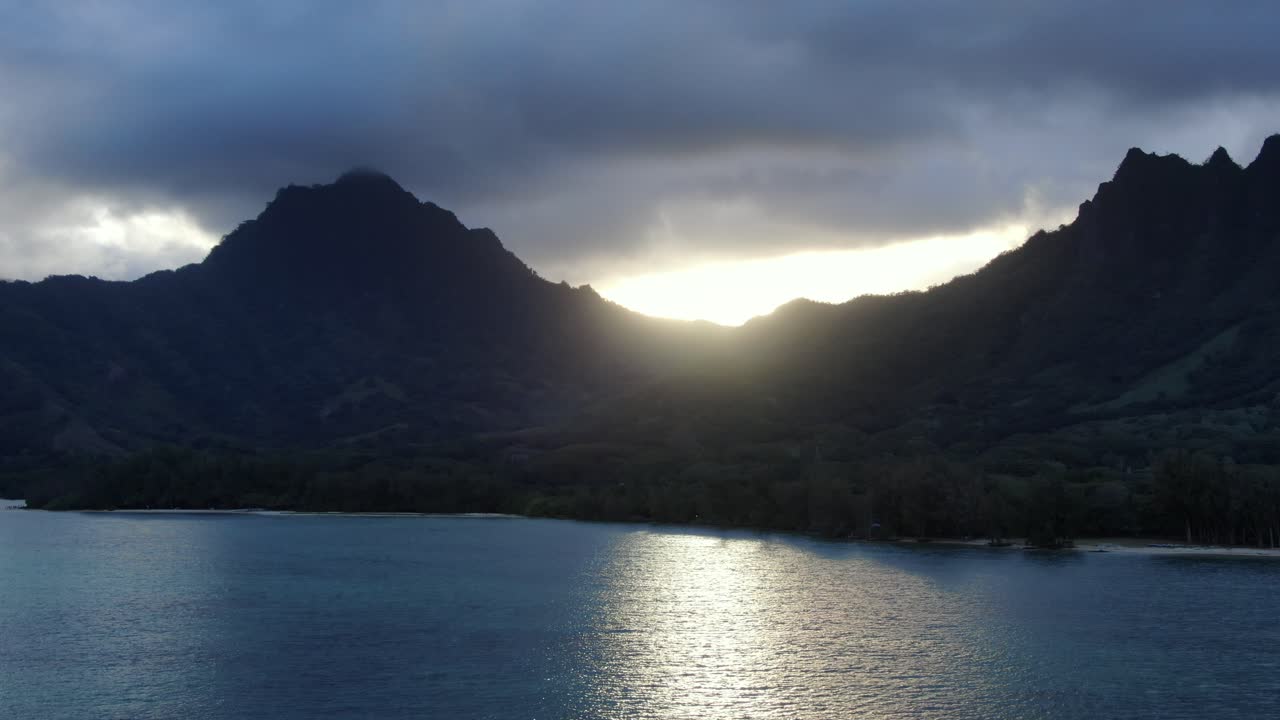 Kane'ohe Bay with a dramatic sunset falling behind the mountain ranges of Oahu casting a reflection on the bay