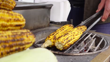 street vendor grilling corn on the cob over charcoal