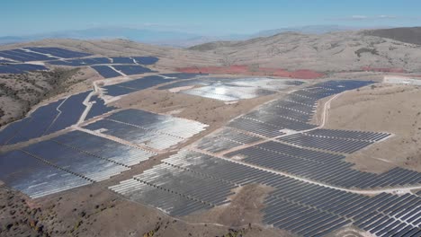 drone over photovoltaic solar power park row panels rural hills sunlight reflect