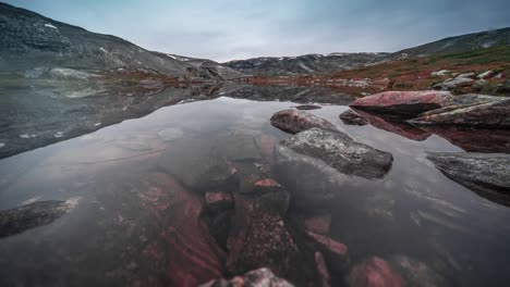 A-shallow-pond-with-transparent-water-and-a-rocky-bottom-in-the-mountainous-area