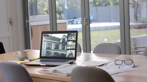 laptop on dining table showing four home security camera views, slow motion