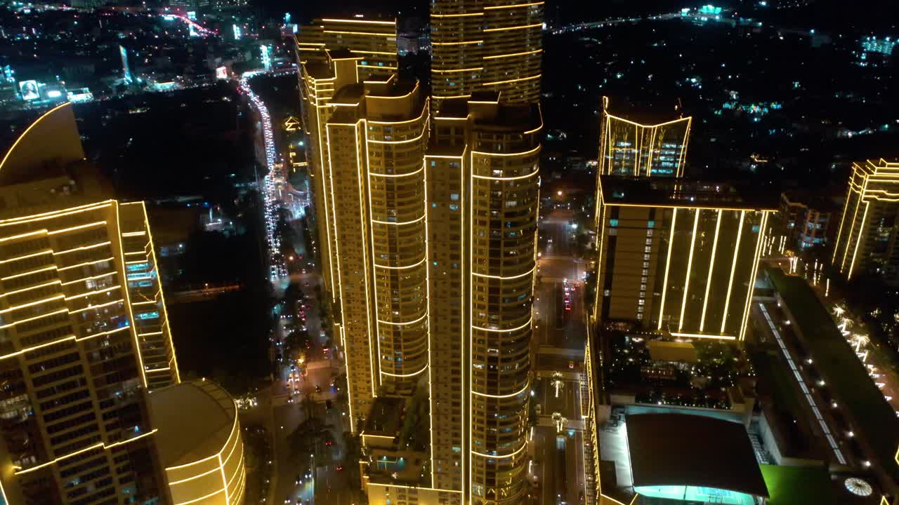 Aerial footage of Rockwell Center and its skyscrapers in Makati, Metro Manila, glowing with lights at night and surrounded by the vibrant energy of the city skyline.