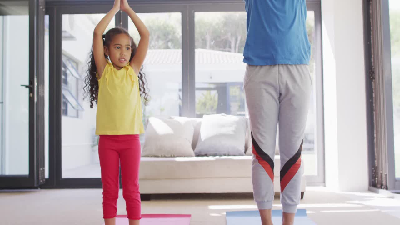 Happy biracial father and daughter doing yoga, meditating together