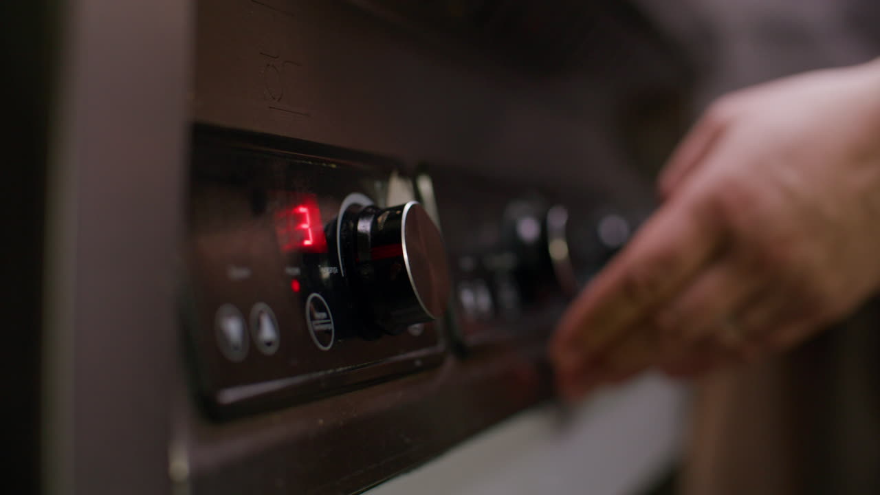 Mano dello chef che regola la manopola della temperatura sul forno nella cucina di un ristorante