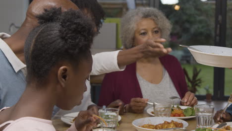 Madre-De-Familia-Pasando-Tazón-De-Patatas-A-Través-De-La-Mesa-De-Comedor