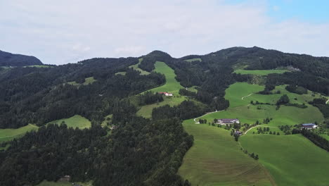 Mountains-and-hills-in-the-Austrian-Alps,-farms-in-the-background