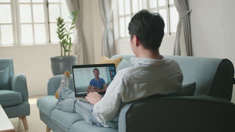 man greeting with colleagues in video conference from laptop at home living room, video in 4k