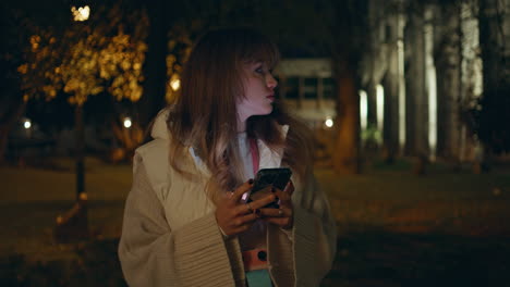 millennial holding cellphone evening urban park closeup. woman messaging