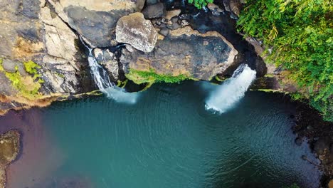 top-down-shot-of-waterfalls-cascading-and-flowing-down-from-a-mountain-cliff-in-morrocco-on-a-hot-and-muggy-day