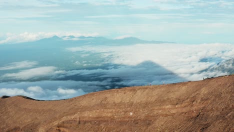 sunrise drone shot following mountain ridge trail and people on it. cloudy valley behind. pan to right. 4k footage.