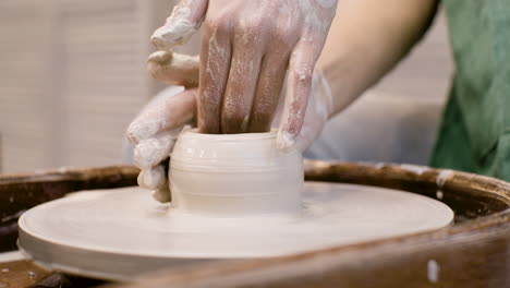 close up view of hands of a clerk modeling ceramic piece on a potter wheel in a workshop 2 1