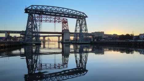 slow aerial dolly in shot overlooking puente transbordador, transporter bridge over the wavy riachuelo river in la boca neighbourhood of buenos aires, argentina