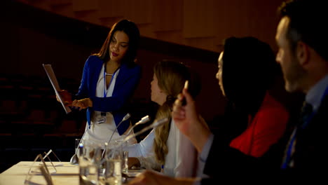 Multi-ethnic-business-people-discussing-over-documents-on-stage-in-auditorium-4k