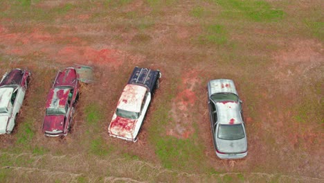 Aerial-shot-of-old,-rusted-cars-abandoned-in-an-open-field---vintage-cars