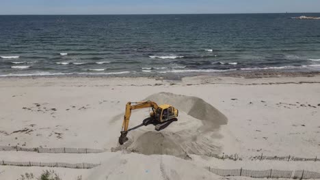 Aerial-drone-footage-of-a-crane-moving-and-redistributing-sand-on-Sandy-Beach,-cohasset,-MA-USA