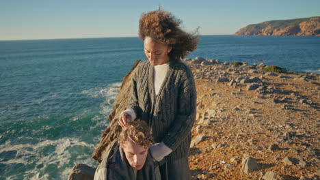tender woman caressing husband at picturesque ocean cliff. love sweethearts