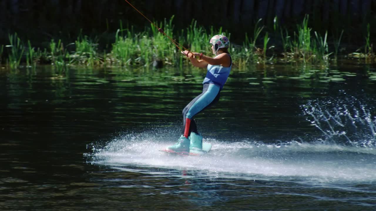 mujer deportiva a bordo deslizándose sobre el agua. niña estudiando wakeboarding en el lago