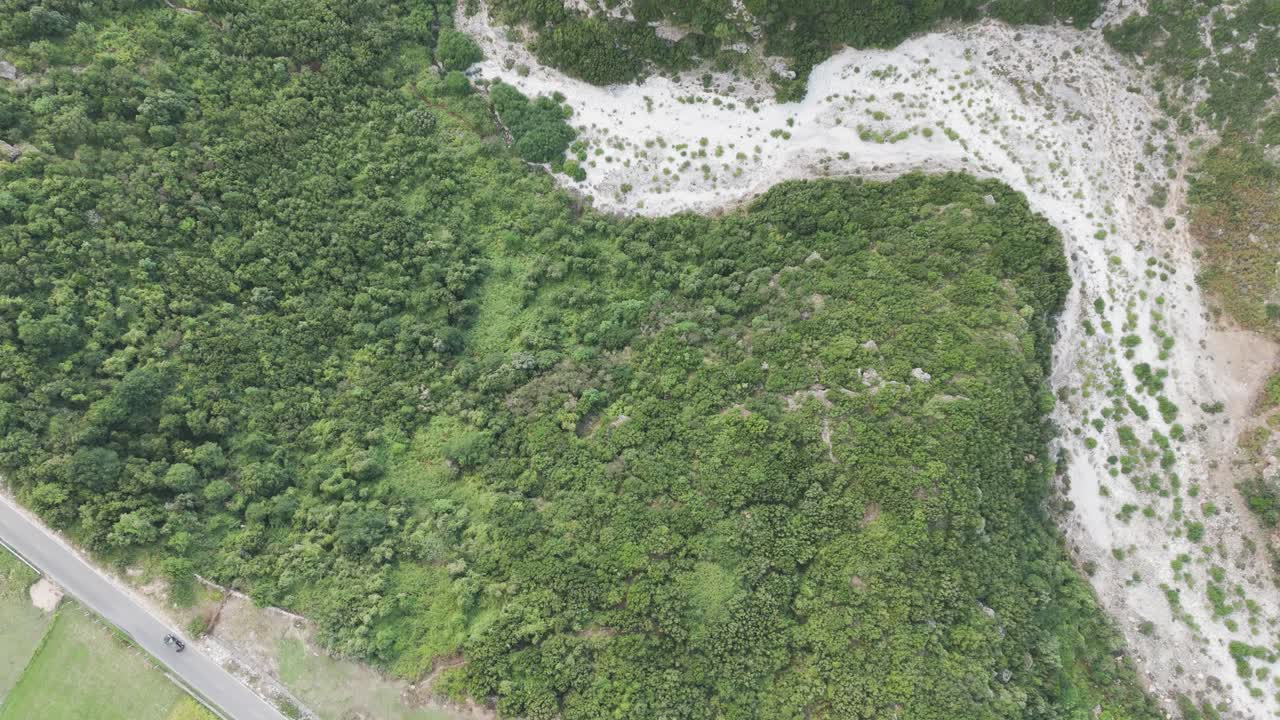 volando sobre un bosque verde cerca del tráfico de la carretera y el lecho seco del río, albania