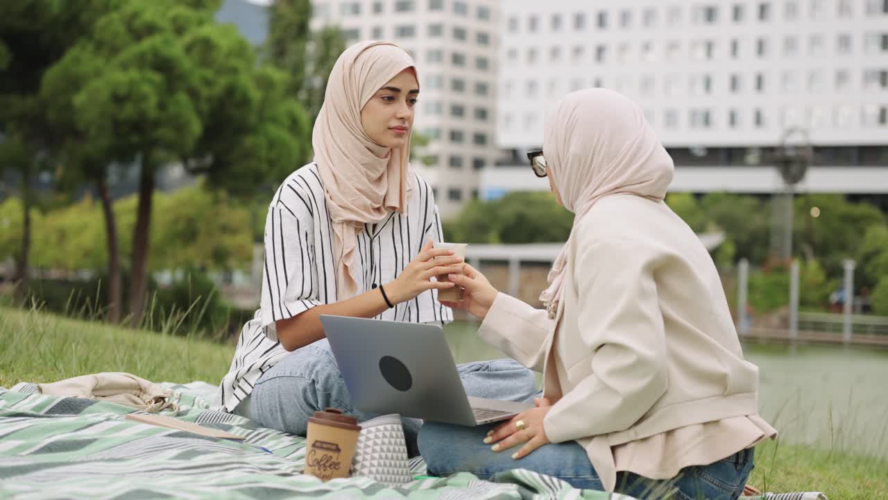 Two women in hijabs having a picnic in the park